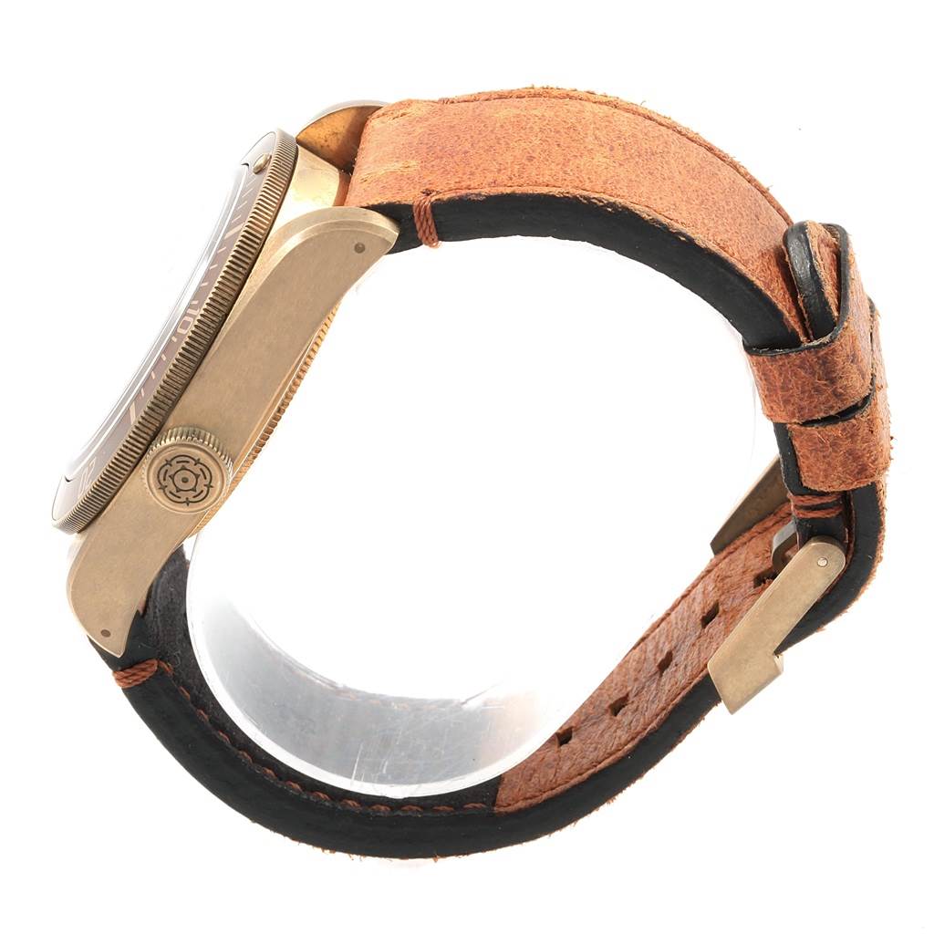 The Heritage Black Bay by Tudor is shown from a side angle, highlighting the watch case, crown, and leather strap.