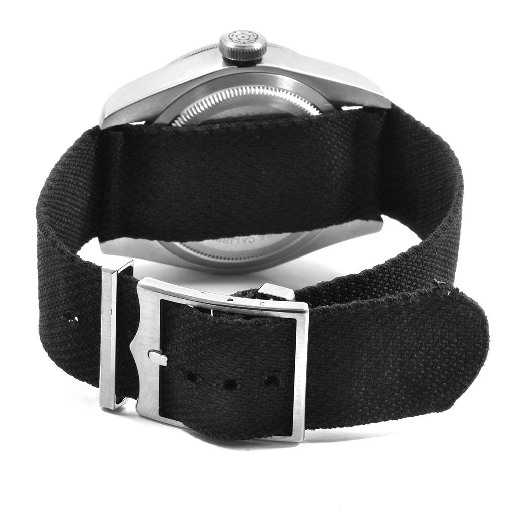 The image shows the back view of a Tudor Heritage Black Bay 79230 Men's Stainless Steel Black Dial 79230 Men's Stainless Steel Black Dial watch, focusing on the case, crown, and fabric strap with the clasp.
