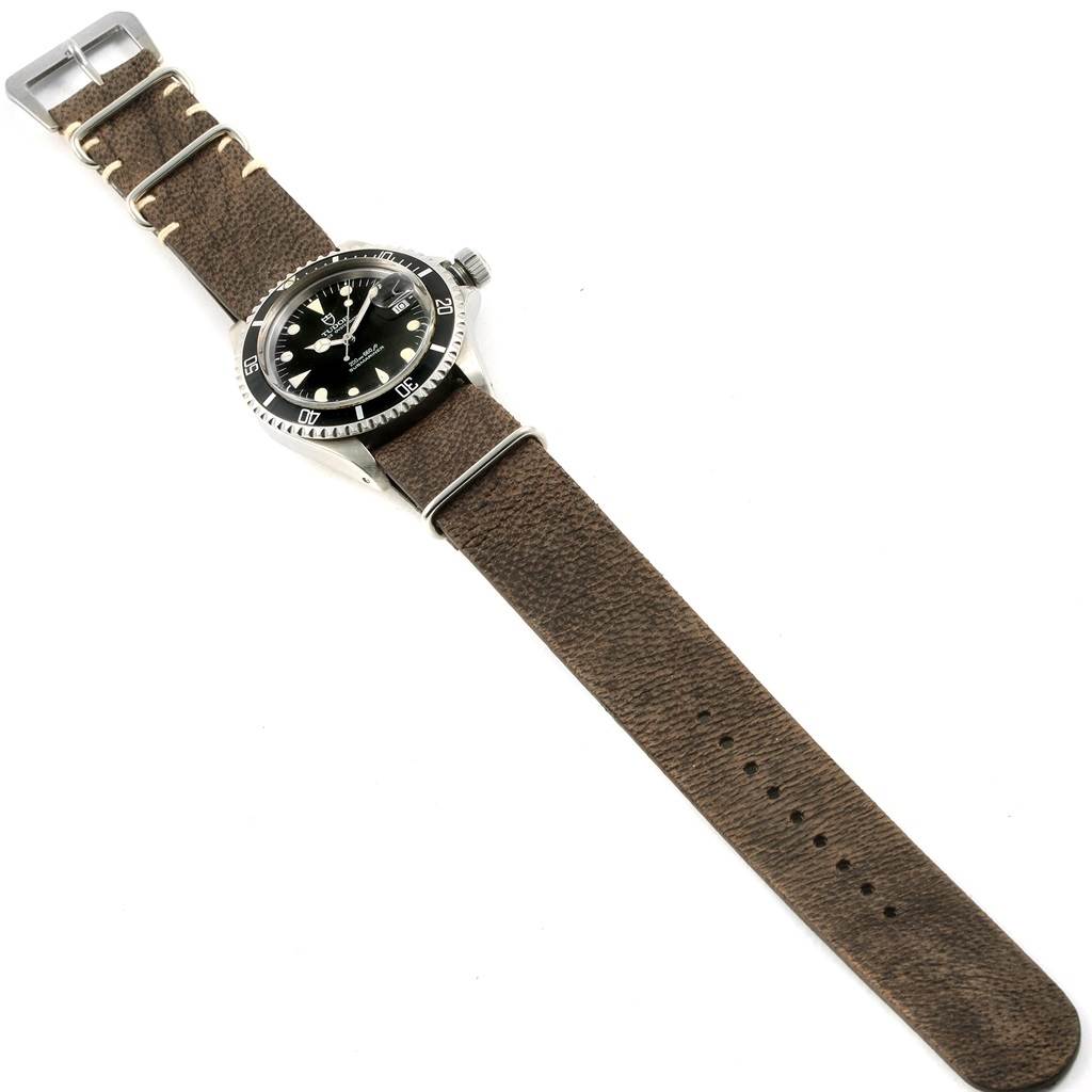 The Tudor Submariner 79090 Men's Stainless Steel Black Dial 79090 Men's Stainless Steel Black Dial watch is shown from a top view, displaying its face, bezel, crown, and brown leather strap.