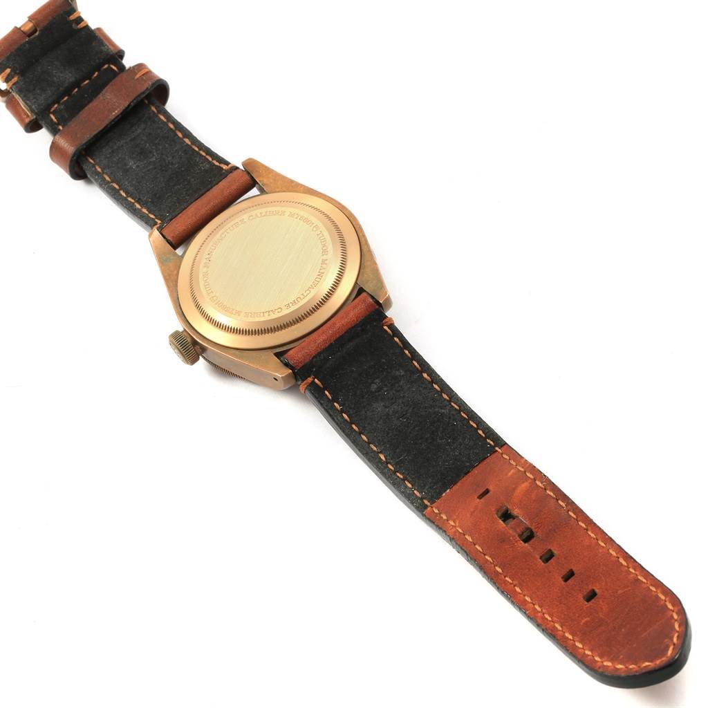 The image shows the back side of the Tudor Heritage Black Bay 79250B Men's Bronze Brown Dial 79250B Men's Bronze Brown Dial watch, highlighting its case back and leather strap.