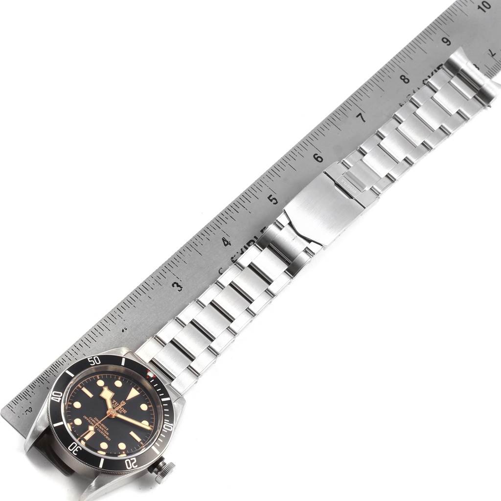 The image shows a top-down view of a Tudor Heritage Black Bay 55020 Men's Stainless Steel Black Dial 55020 Men's Stainless Steel Black Dial watch alongside a measuring ruler.