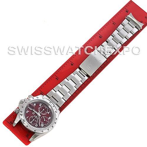 The image shows a top-down view of a Tudor Tiger 79280 Men's Stainless Steel Burgundy Dial 79280 Men's Stainless Steel Burgundy Dial model watch, displaying the dial, bracelet, and clasp against a red ruler.