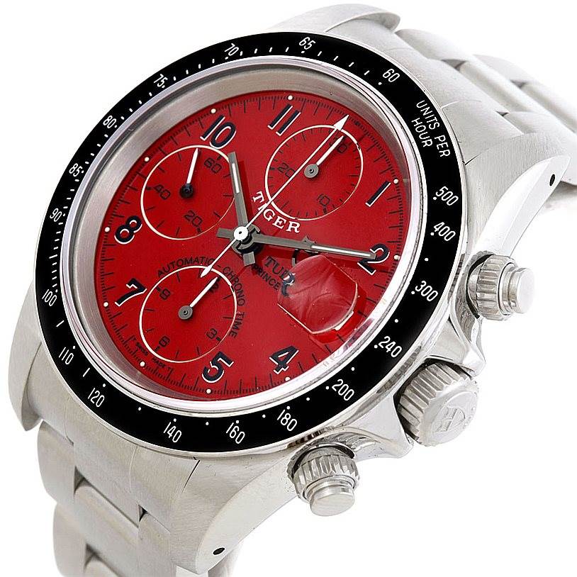 The image shows a close-up view of the Tudor Prince watch featuring a red dial, crown, chronograph pushers, and partial stainless steel bracelet.