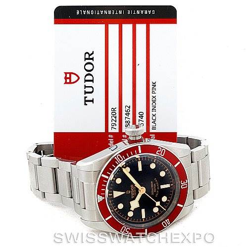 The Tudor Heritage Black Bay 79220R Men
s Stainless Steel Black Dial 79220R Men
s Stainless Steel Black Dial watch is shown from the front, showcasing its face, bezel, and bracelet, with an Best Quality
ity card behind it.