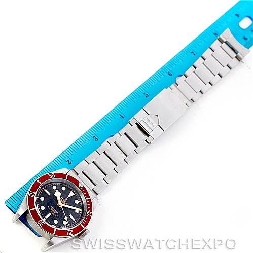 The Tudor Heritage Black Bay 79220R Men
s Stainless Steel Black Dial 79220R Men
s Stainless Steel Black Dial watch is shown from a top-down angle, displaying the entire bracelet and face next to a blue ruler.