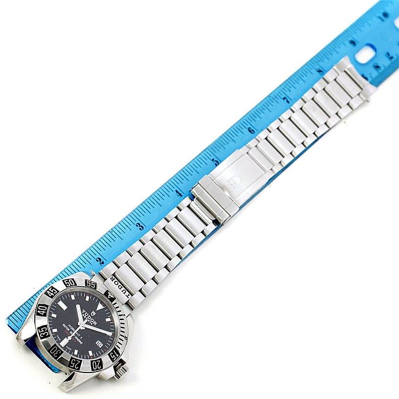 The image shows a top-down view of a Tudor Hydronaut 20040 Men
s Stainless Steel Black Dial 20040 Men
s Stainless Steel Black Dial watch with its stainless steel strap alongside a blue ruler.