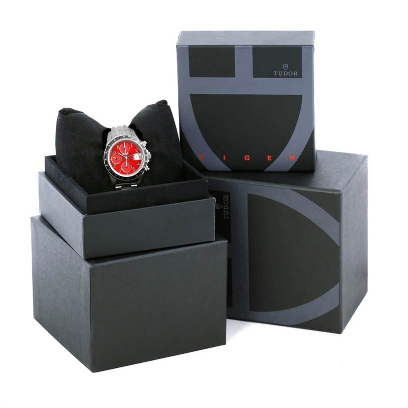 The image shows a Tudor Prince model watch with a red face, presented in its branded packaging, including boxes and cushion.