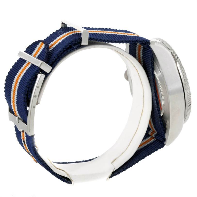 The image shows the side view of a Tudor Heritage Chrono 79220R Men's Stainless Steel Blue Dial 79220R Men's Stainless Steel Blue Dial watch, highlighting its case and blue-striped fabric strap.