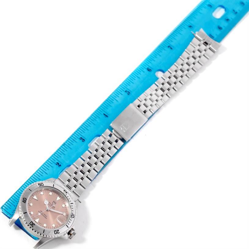 The Tudor Submariner 75190 Men's Stainless Steel Pink Dial 75190 Men's Stainless Steel Pink Dial watch is shown laid flat next to a ruler, displaying its face and metal bracelet.