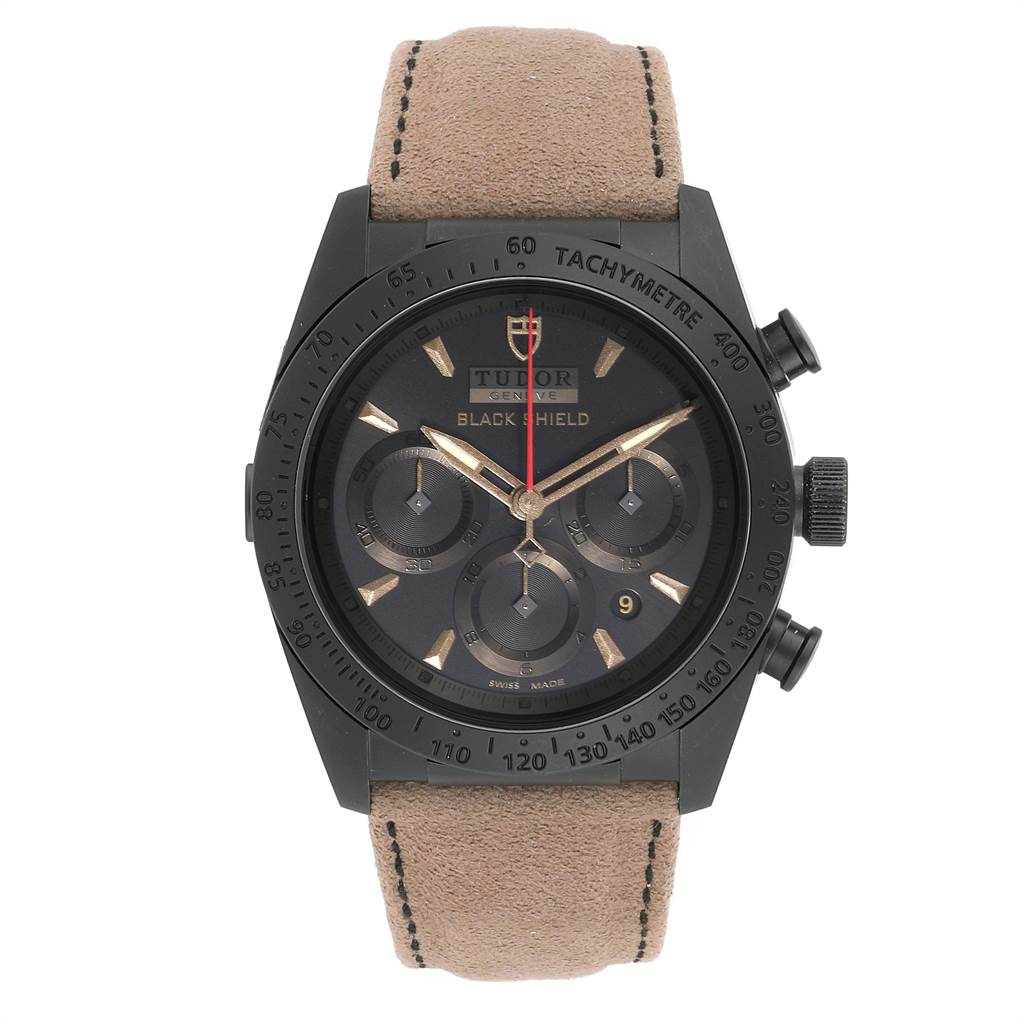 The image shows a front view of the Tudor Fastrider 42000CN Men's Stainless Steel Black Dial 42000CN Men's Stainless Steel Black Dial Black Shield watch with a beige leather strap and black tachymeter bezel.
