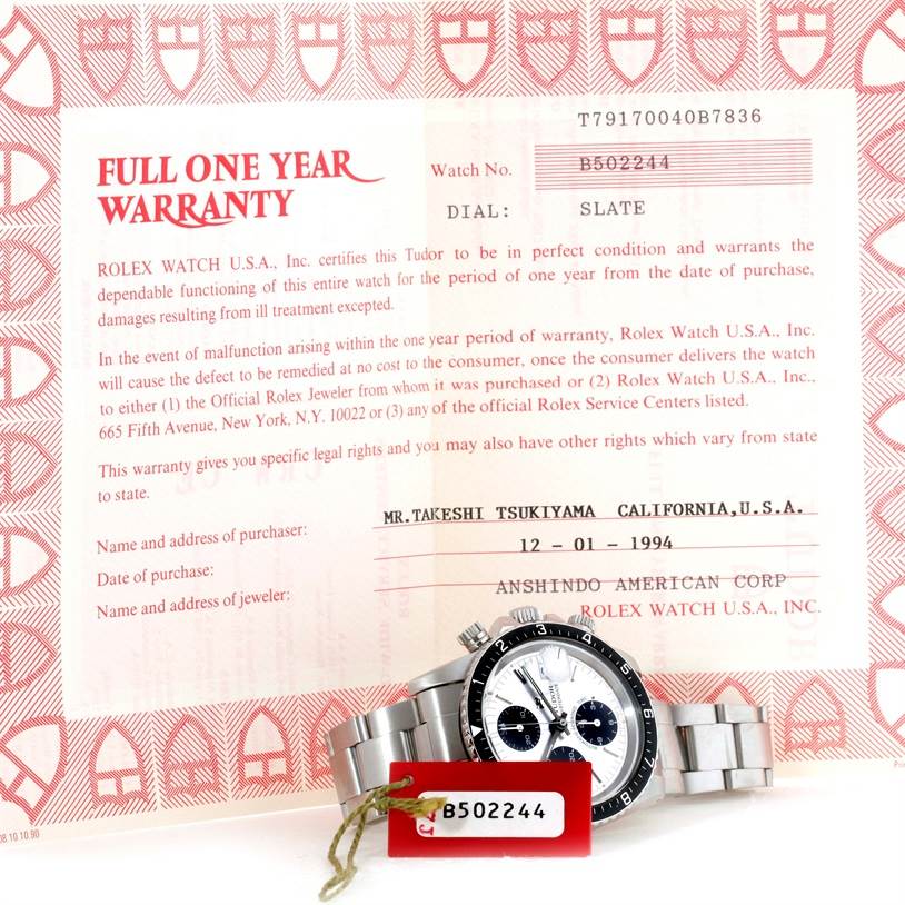 The image shows a frontal view of a Tudor Big Block 79170 Men's Stainless Steel Silver Dial 79170 Men's Stainless Steel Silver Dial watch with a warranty card in the background.