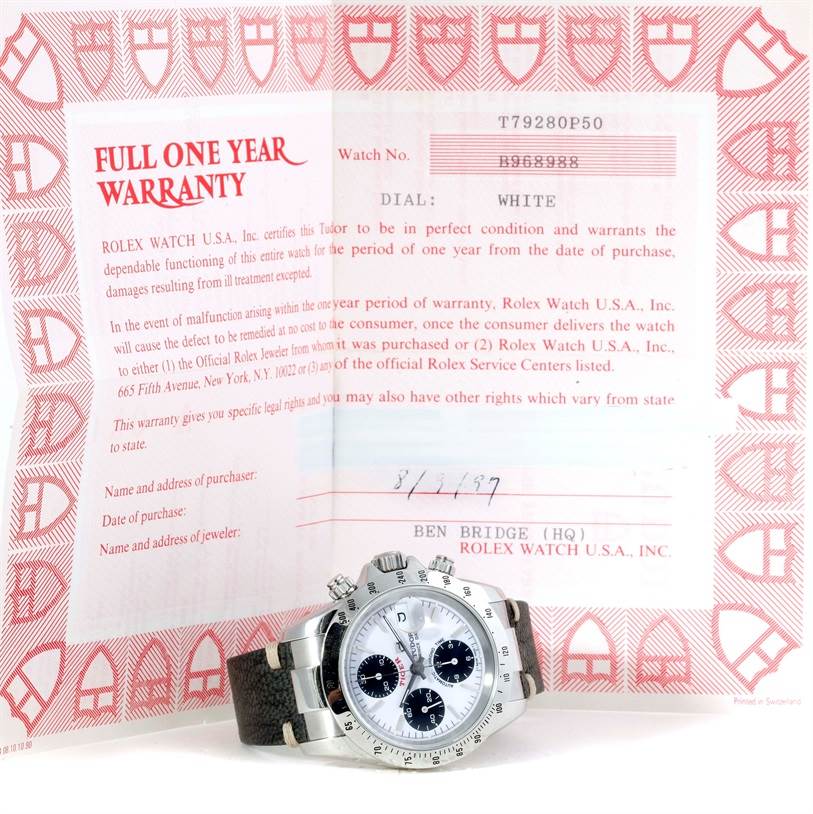 The image shows a Tudor Tiger 79280 Men's Stainless Steel White Dial 79280 Men's Stainless Steel White Dial wristwatch resting on its one-year warranty documentation.