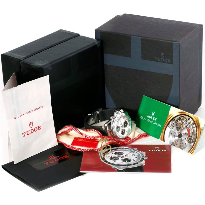 The Tudor Tiger 79280 Men's Stainless Steel White Dial 79280 Men's Stainless Steel White Dial watch and accessories are shown at an angle, accompanied by booklets, a warranty card, and the original boxes.