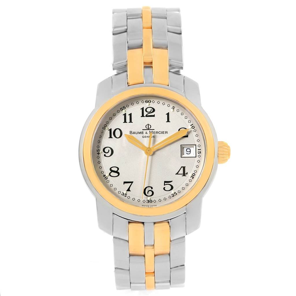 The image shows a front view of a Capeland model by Baume & Mercier, featuring the dial, hands, date window, and part of the metal bracelet.