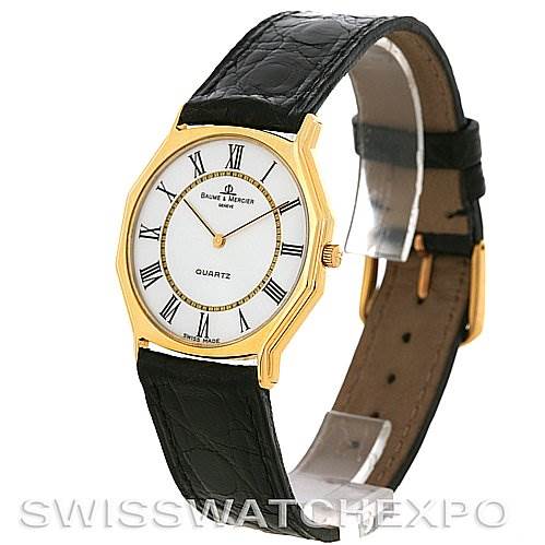 The image shows a Vintage Baume & Mercier 1505735 Men's Yellow Gold White Dial 1505735 Men's Yellow Gold White Dial 14k Yellow Gold Quartz Watch from an angled view highlighting the dial and black leather strap.