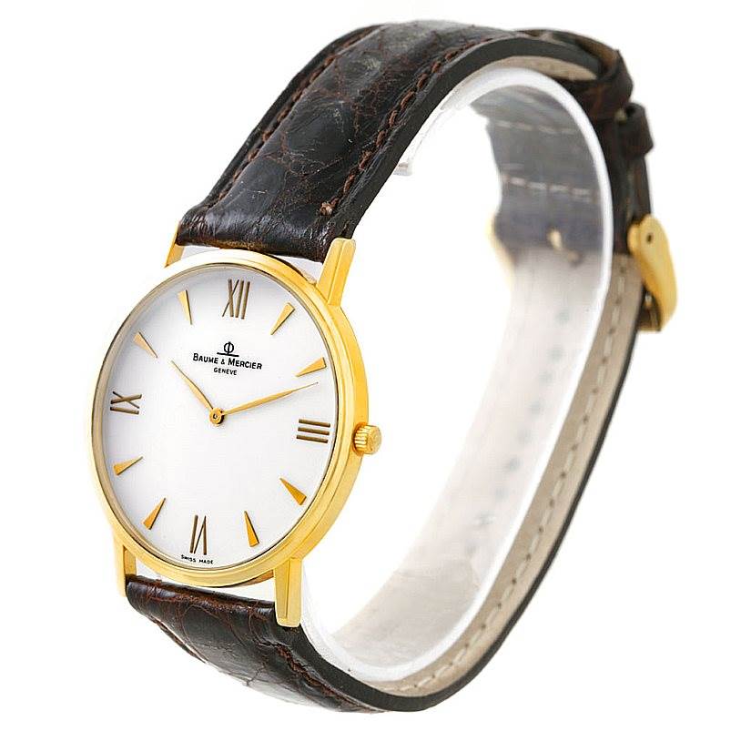 The image shows a side view of a Baume & Mercier Classima 8069 Men's Yellow Gold White Dial 8069 Men's Yellow Gold White Dial watch, featuring a gold case, white dial, and black leather strap.