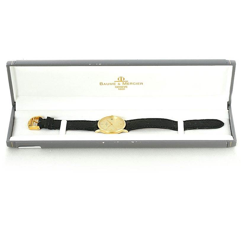 The image shows a Baume & Mercier Classima 6149 Men's Yellow Gold Champagne Dial 6149 Men's Yellow Gold Champagne Dial watch in a box, displaying the face, strap, and buckle.