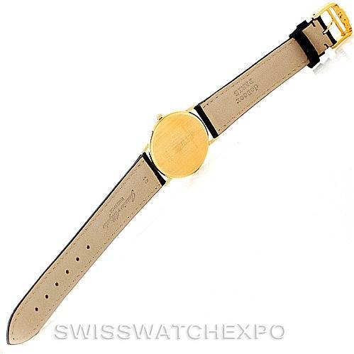 The image shows the back view of the Baume & Mercier Classima MV045088 Men's Yellow Gold White Dial MV045088 Men's Yellow Gold White Dial watch, displaying its leather strap and gold case back.