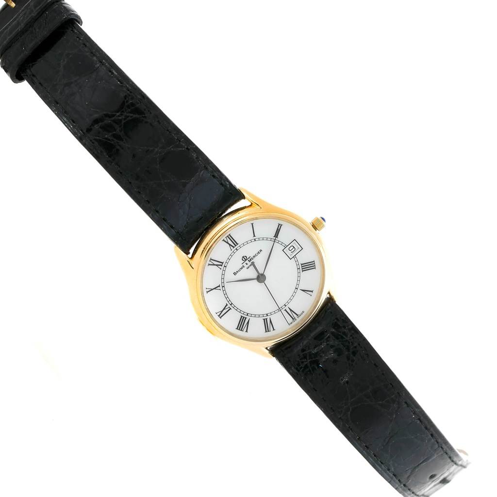 This image shows a Baume & Mercier Classima 95248 Men's Yellow Gold White Dial 95248 Men's Yellow Gold White Dial watch angled to display its dial, black strap, and gold casing.