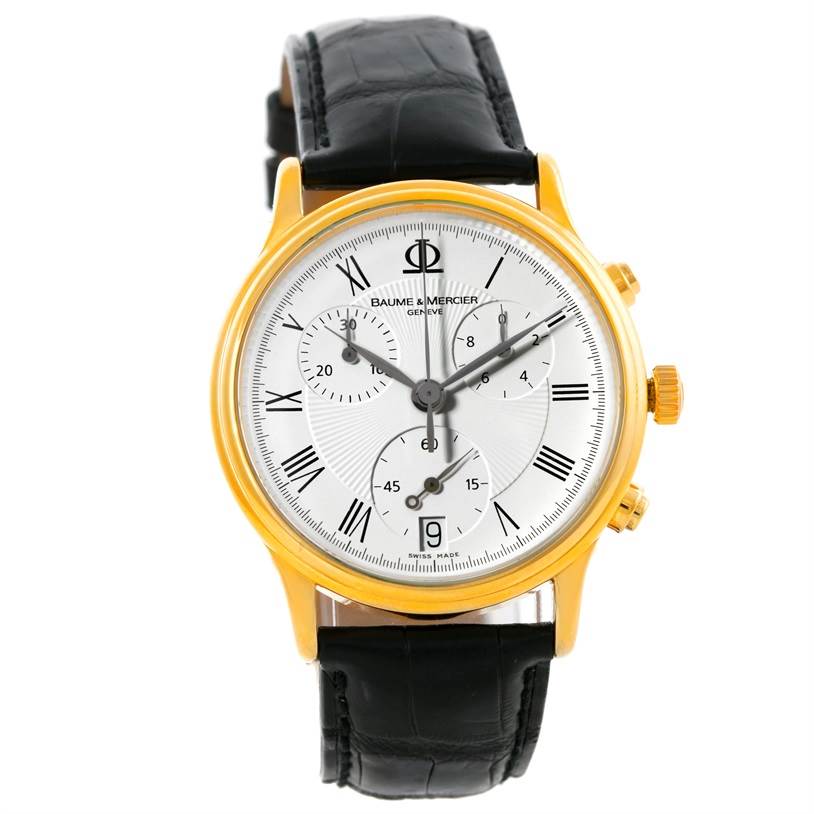 The image shows a front view of a Baume & Mercier Classima Men's Yellow Gold White Dial Men's Yellow Gold White Dial watch with a gold case, black leather strap, and visible subdials.