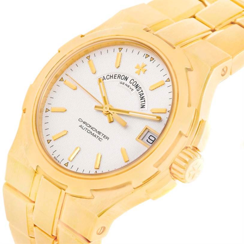 The Vacheron Constantin Overseas 42050/423J Men's Yellow Gold Silver Dial 42050/423J Men's Yellow Gold Silver Dial watch is shown from an oblique angle, highlighting the dial, crown, bezel, and part of the bracelet.