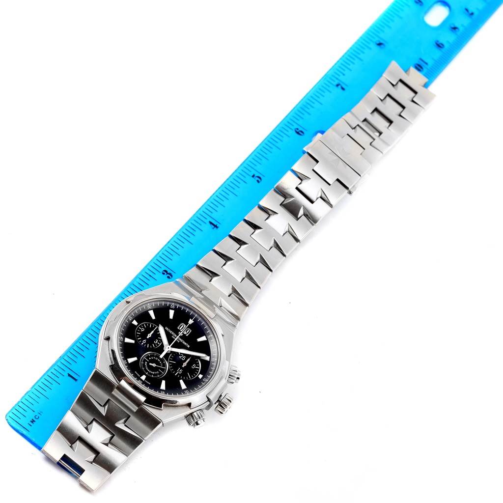 The Vacheron Constantin Overseas 49150.B01A.9097 Men's Stainless Steel Black Dial 49150.B01A.9097 Men's Stainless Steel Black Dial watch is shown from an overhead view, displaying the full bracelet, case, and dial alongside a ruler for scale.