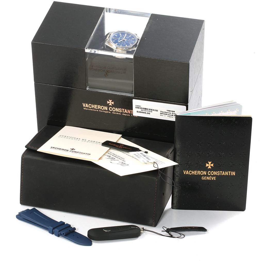 The image shows a Vacheron Constantin Overseas 49150.B01A.9097 Men's Stainless Steel Blue Dial 49150.B01A.9097 Men's Stainless Steel Blue Dial watch with its box, documents, additional strap, and accessories from an angle in front.