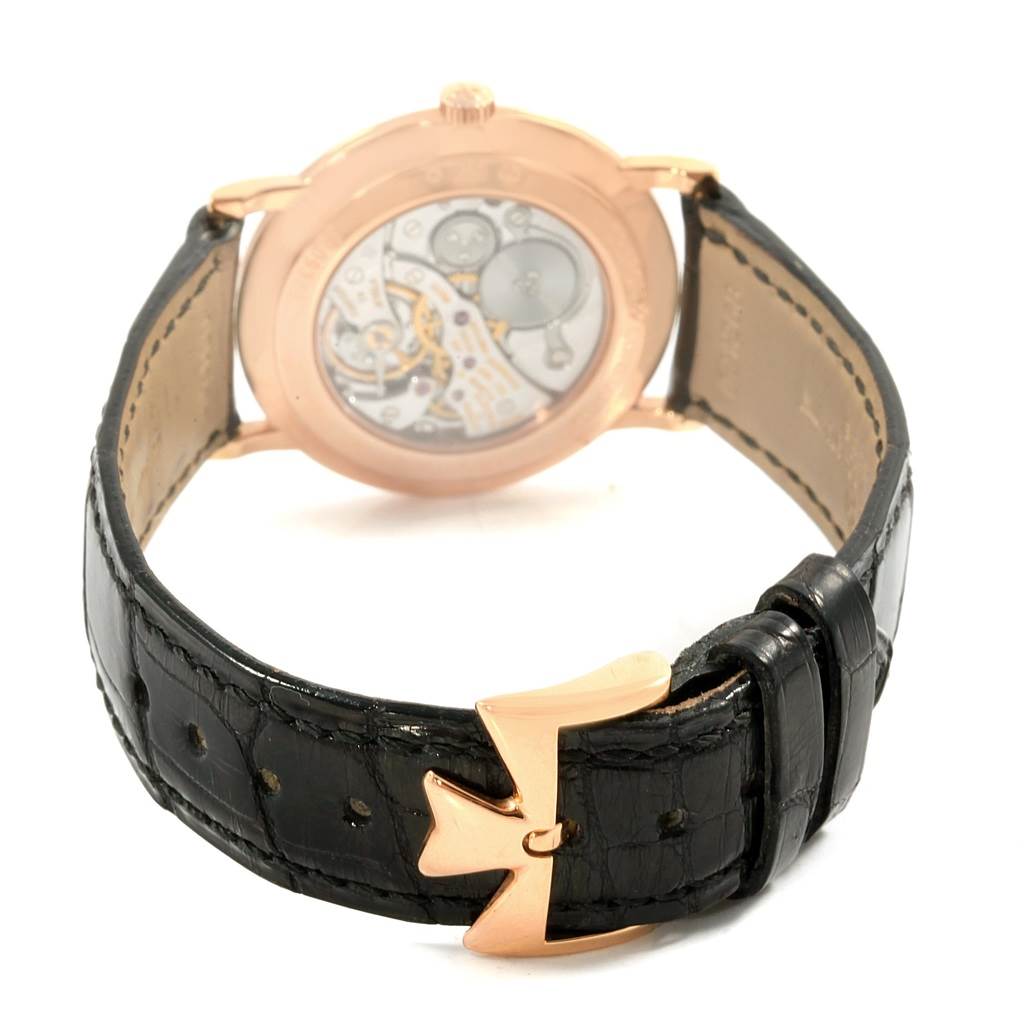 The image shows the back of a Patrimony model watch by Vacheron Constantin, highlighting the movement and black strap with a distinctive clasp.