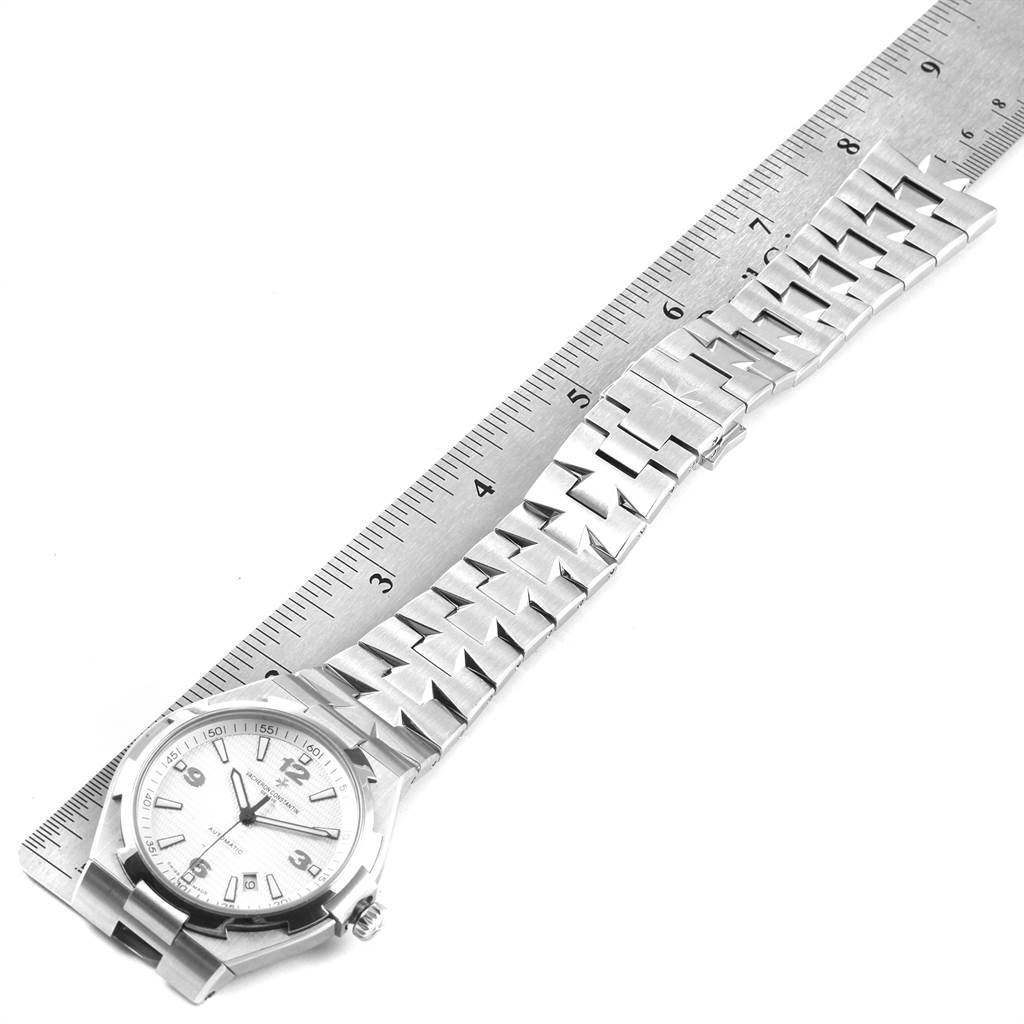 The Vacheron Constantin Overseas 47040B01A-9093 Men's Stainless Steel Silver Dial 47040B01A-9093 Men's Stainless Steel Silver Dial watch is shown flat with its stainless steel bracelet alongside a ruler for scale.