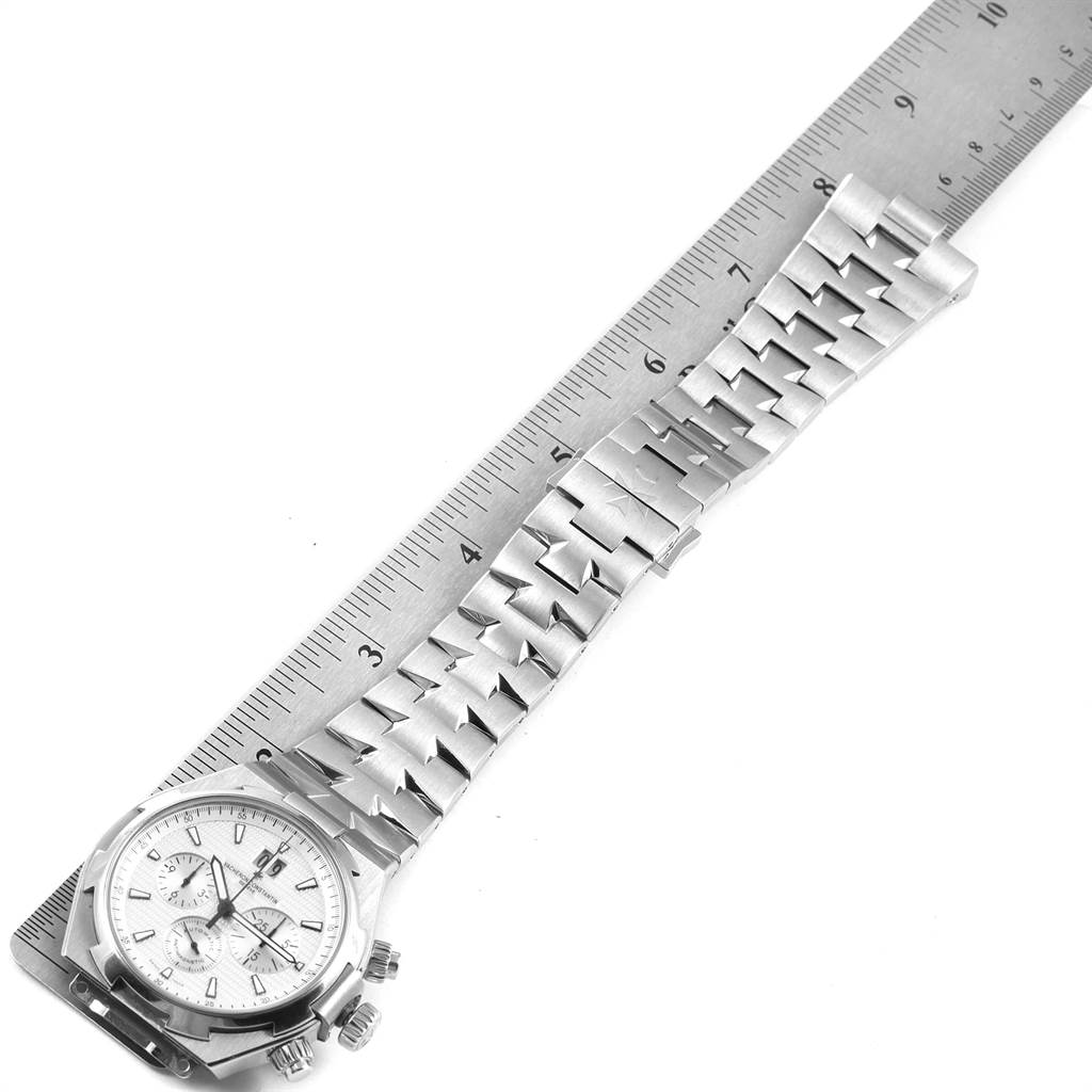 The image shows a Vacheron Constantin Overseas 49150 Men's Stainless Steel Silver Dial 49150 Men's Stainless Steel Silver Dial model watch laid flat with a ruler measuring its band length.