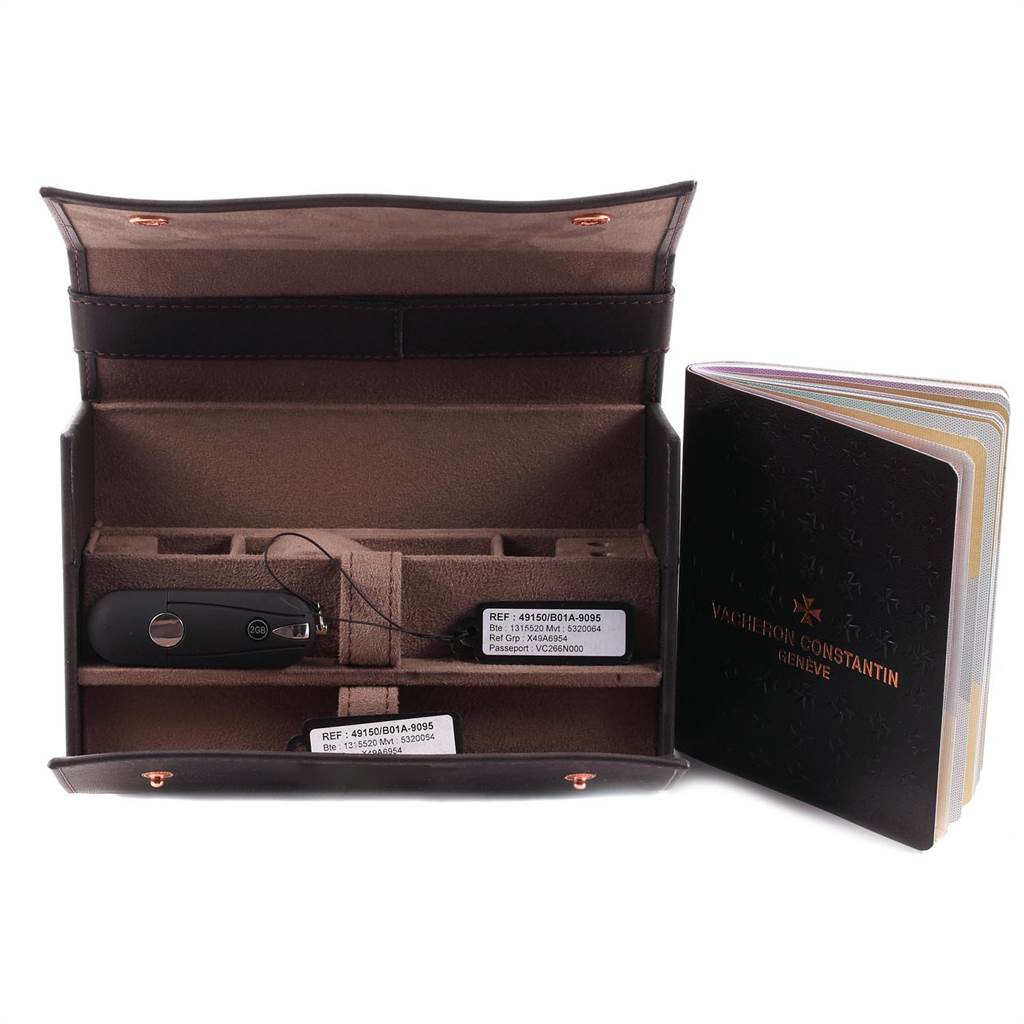 This image shows the opened case for a Vacheron Constantin Overseas 49150 Men's Stainless Steel Silver Dial 49150 Men's Stainless Steel Silver Dial watch, along with tags, a key, and a booklet.