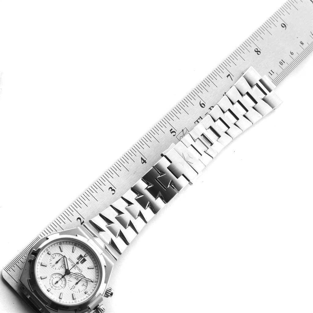 This image shows a Vacheron Constantin Overseas 49150 Men's Stainless Steel Silver Dial 49150 Men's Stainless Steel Silver Dial model watch laid down flat with a ruler measuring its bracelet.