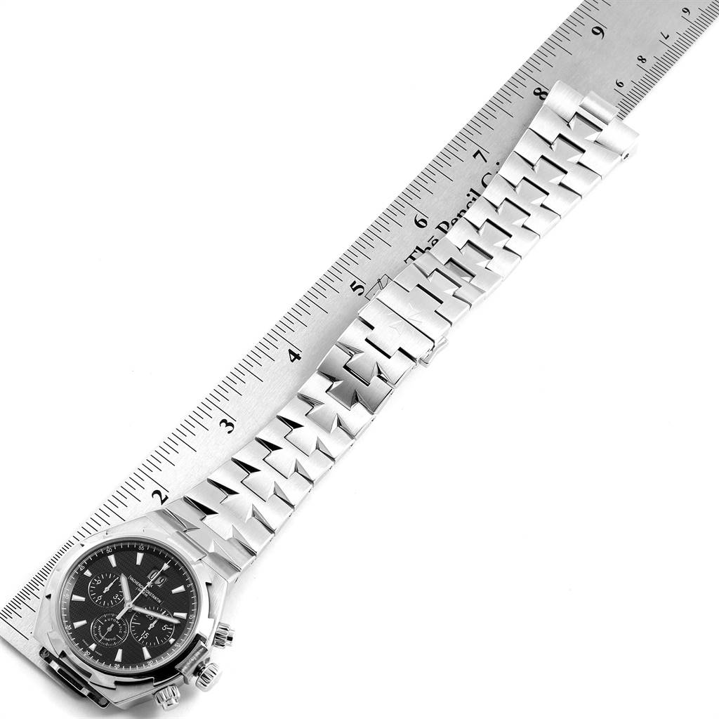 The image shows the Vacheron Constantin Overseas 49150 Men's Stainless Steel Black Dial 49150 Men's Stainless Steel Black Dial watch at an angle revealing the dial and bracelet, placed next to a ruler for measurement.