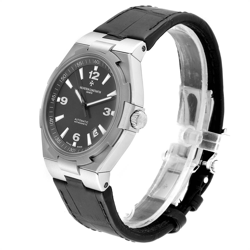 The image shows a Vacheron Constantin Overseas 47040/000W-9500 Men's Stainless Steel Black Dial 47040/000W-9500 Men's Stainless Steel Black Dial watch at an angle highlighting the watch face, crown, and black leather strap.