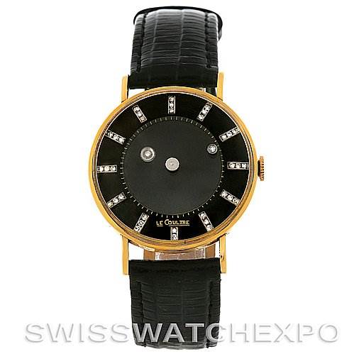 The image shows a front view of a vintage Jaeger LeCoultre watch with a black strap, gold case, and minimalist black dial with diamond markers.
