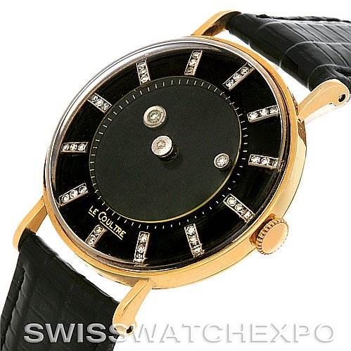 The image shows a three-quarter view of a vintage Jaeger LeCoultre watch with a gold case, black dial, and diamond hour markers.