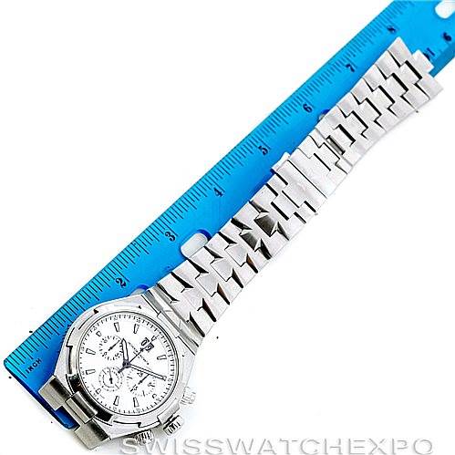 The image shows a Vacheron Constantin Overseas 49150 Men
s Stainless Steel Silver Dial 49150 Men
s Stainless Steel Silver Dial model watch laid flat next to a blue ruler, displaying its face, bezel, and bracelet.