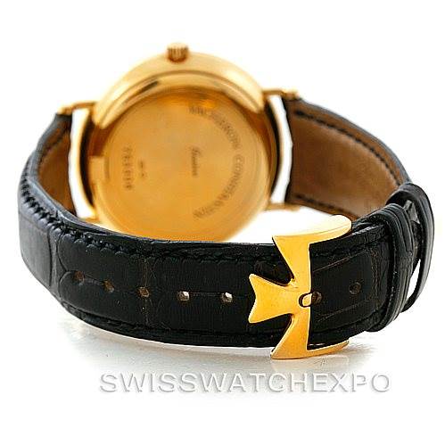 The image shows the back of a Vintage Vacheron Constantin watch, highlighting the gold case back and black leather strap with a unique buckle.