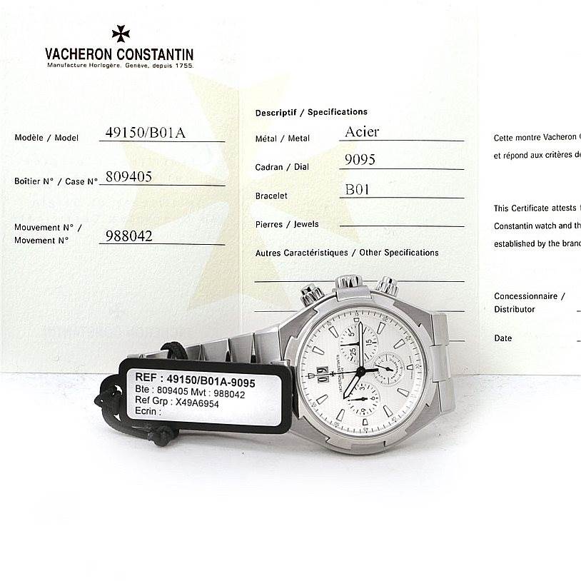 The image shows a Vacheron Constantin Overseas 49150 Men's Stainless Steel Silver Dial 49150 Men's Stainless Steel Silver Dial watch displayed flat with visible front dial, next to its certificate and reference tag.