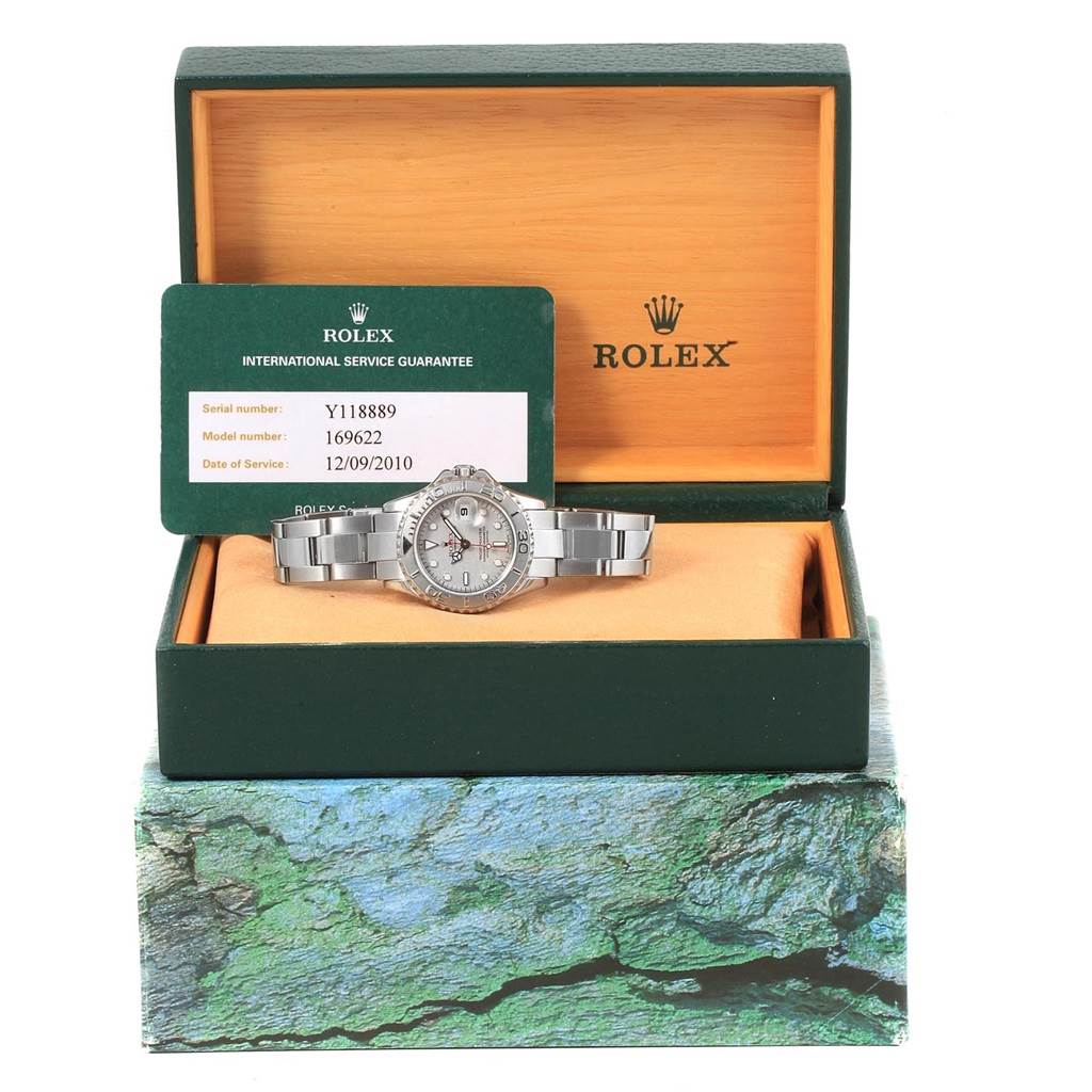 The image shows a Rolex Yacht-Master 169622 Women's Stainless Steel Silver Dial 169622 Women's Stainless Steel Silver Dial watch resting in an open box with its international service guarantee card.