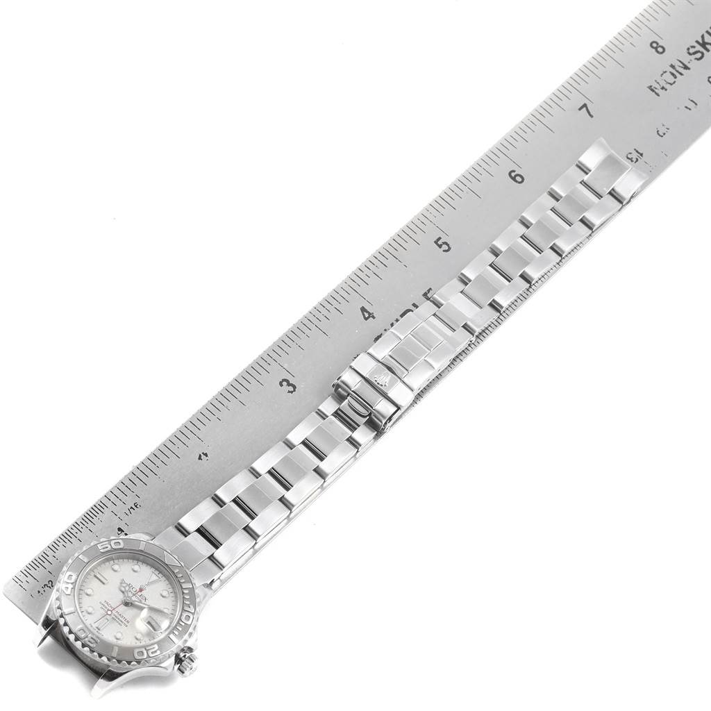 The Rolex Yacht-Master 169622 Women's Stainless Steel Silver Dial 169622 Women's Stainless Steel Silver Dial watch is shown from an angled top-down view, displaying its face, band, and clasp against a ruler.