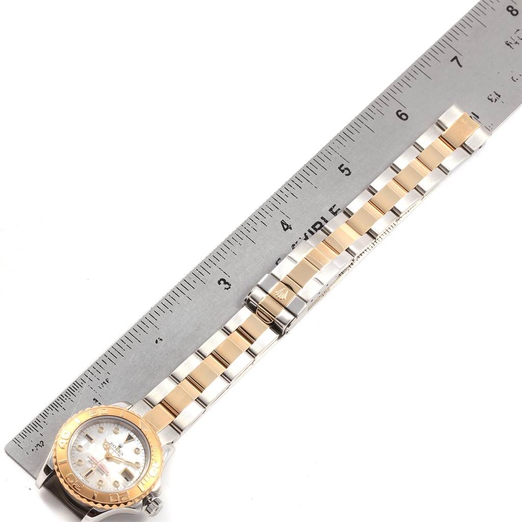 The image shows a Rolex Yacht-Master 169623 Women's Steel and Gold (two tone) Mother of Pearl Dial 169623 Women's Steel and Gold (two tone) Mother of Pearl Dial watch placed next to a ruler, highlighting its band and clasps.
