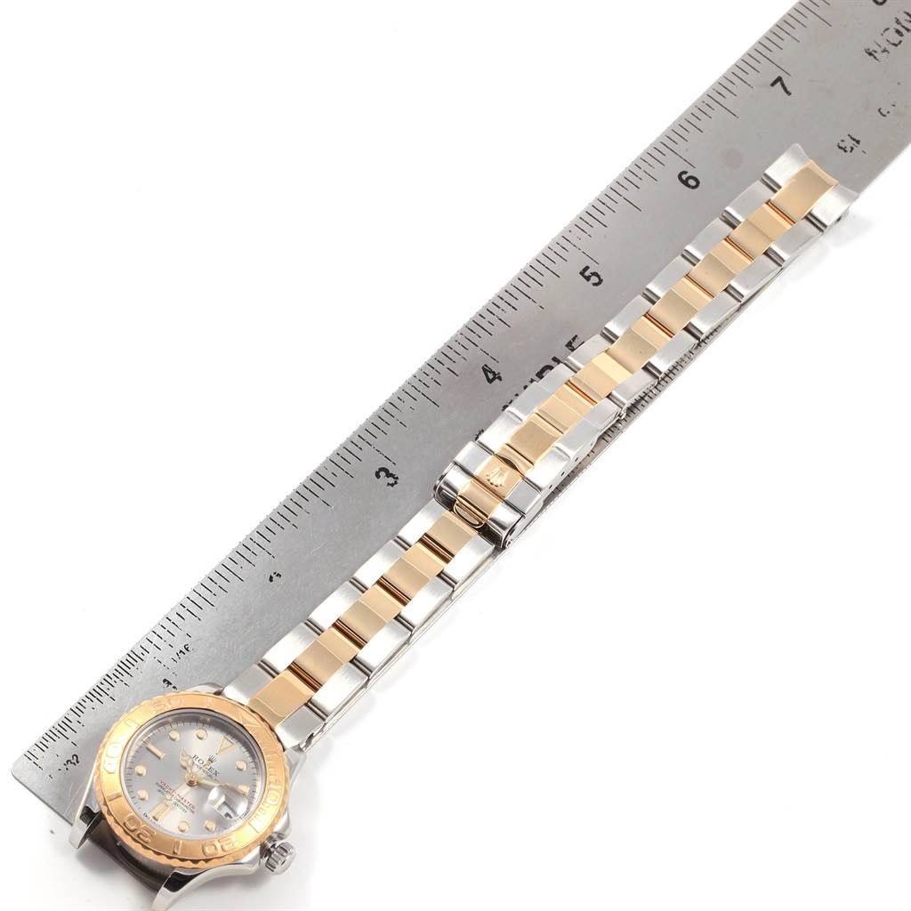 The image shows a top-down view of a Rolex Yacht-Master 169623 Men
s Steel and Gold (two tone) Grey Dial 169623 Men
s Steel and Gold (two tone) Grey Dial watch, including its dial, bezel, and two-tone bracelet next to a ruler.