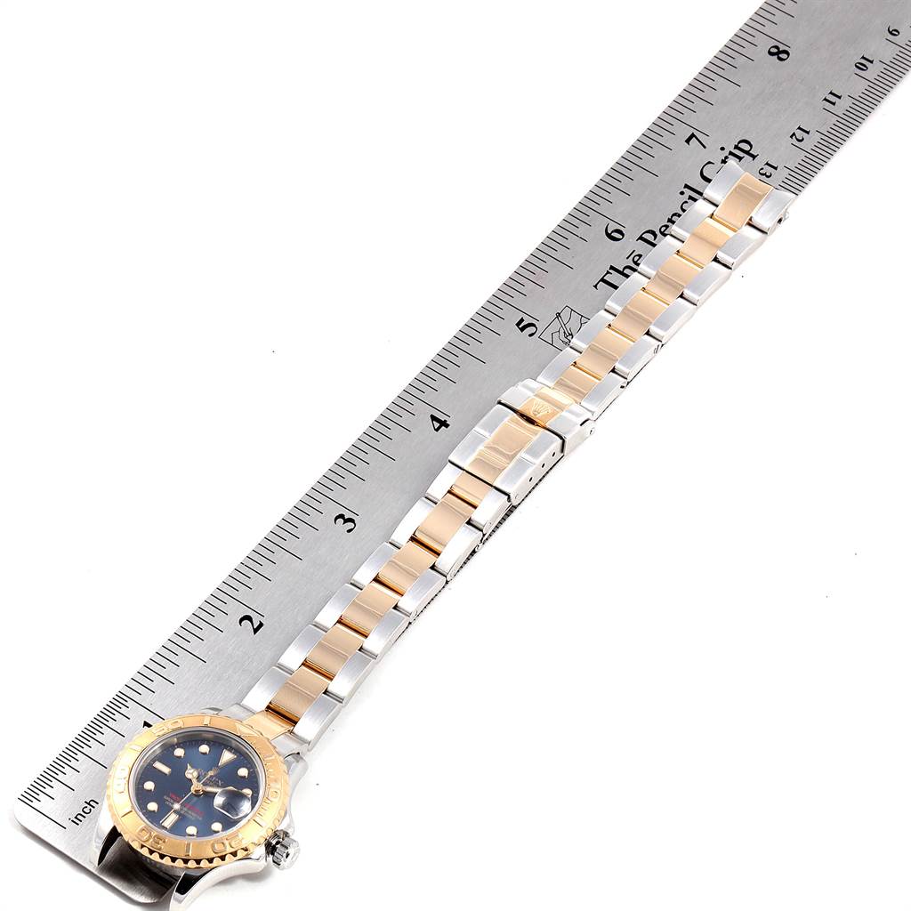 The image shows the Rolex Yacht-Master 169623 Women's Steel and Gold (two tone) Blue Dial 169623 Women's Steel and Gold (two tone) Blue Dial watch laid flat by a ruler, highlighting the bracelet and part of the watch face.