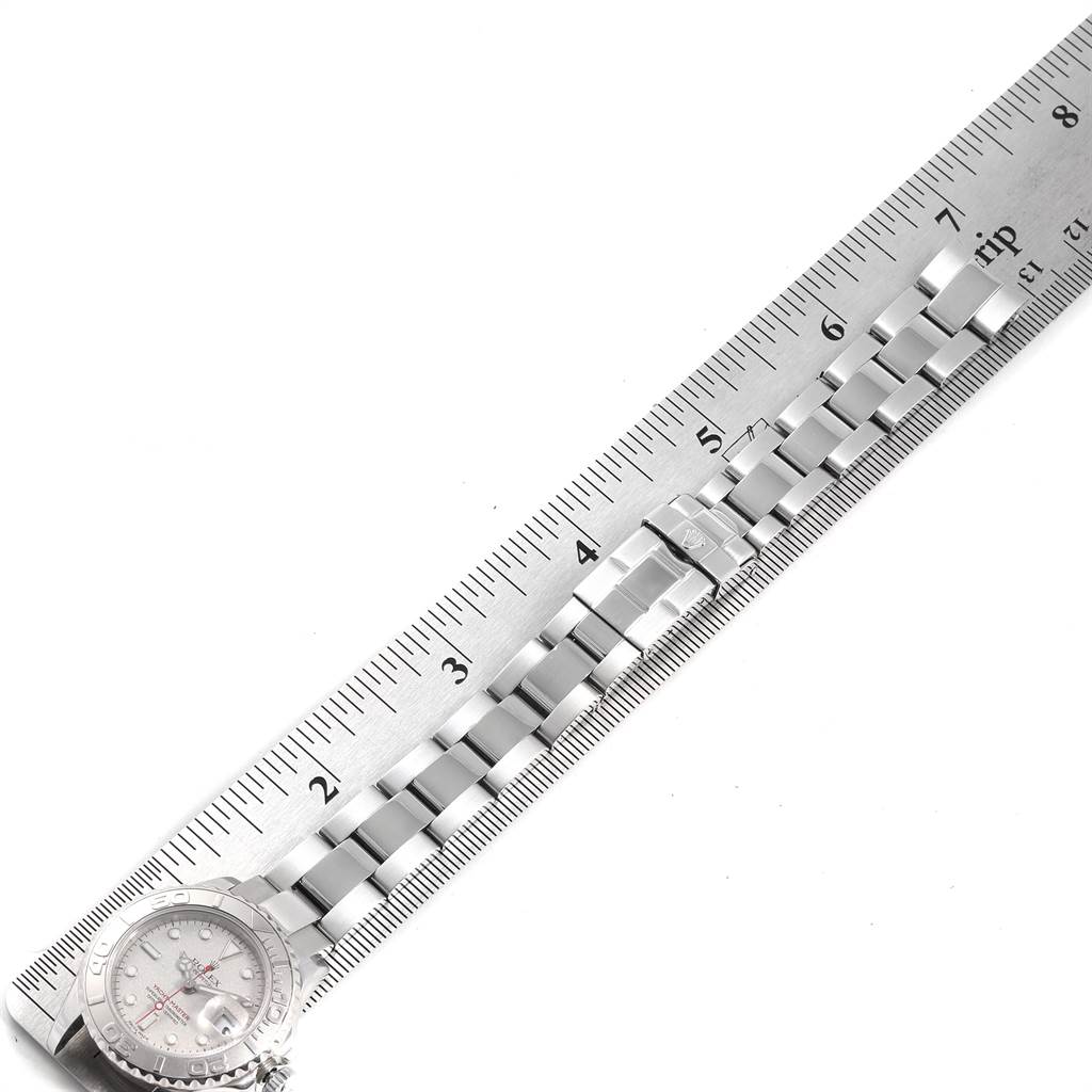 The image shows a Rolex Yacht-Master 169622 Women
s Stainless Steel Silver Dial 169622 Women
s Stainless Steel Silver Dial watch lying next to a ruler, displaying the bracelet and a partial view of the watch face.