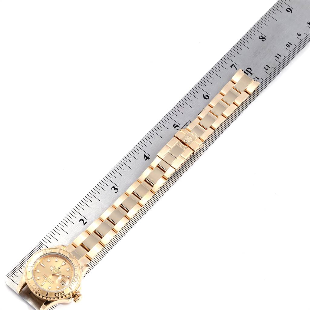 The image shows a Rolex Yacht-Master 69628 Women's Yellow Gold Champagne Dial 69628 Women's Yellow Gold Champagne Dial watch with its bracelet measured beside a metal ruler.