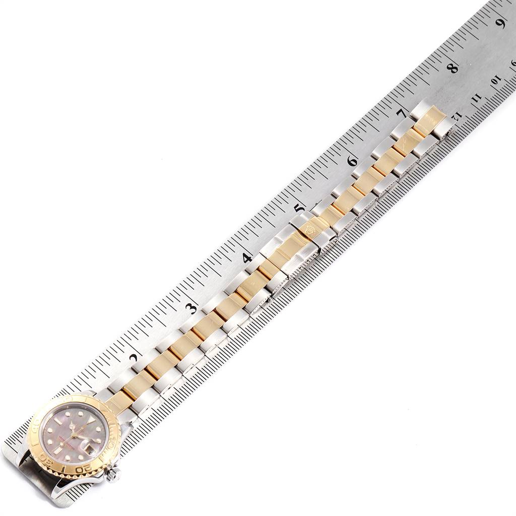 The Rolex Yacht-Master 169623 Women's Steel and Gold (two tone) Mother of Pearl Dial 169623 Women's Steel and Gold (two tone) Mother of Pearl Dial watch is shown from a top-down angle, featuring the face and stainless steel and gold bracelet alongside a ruler.