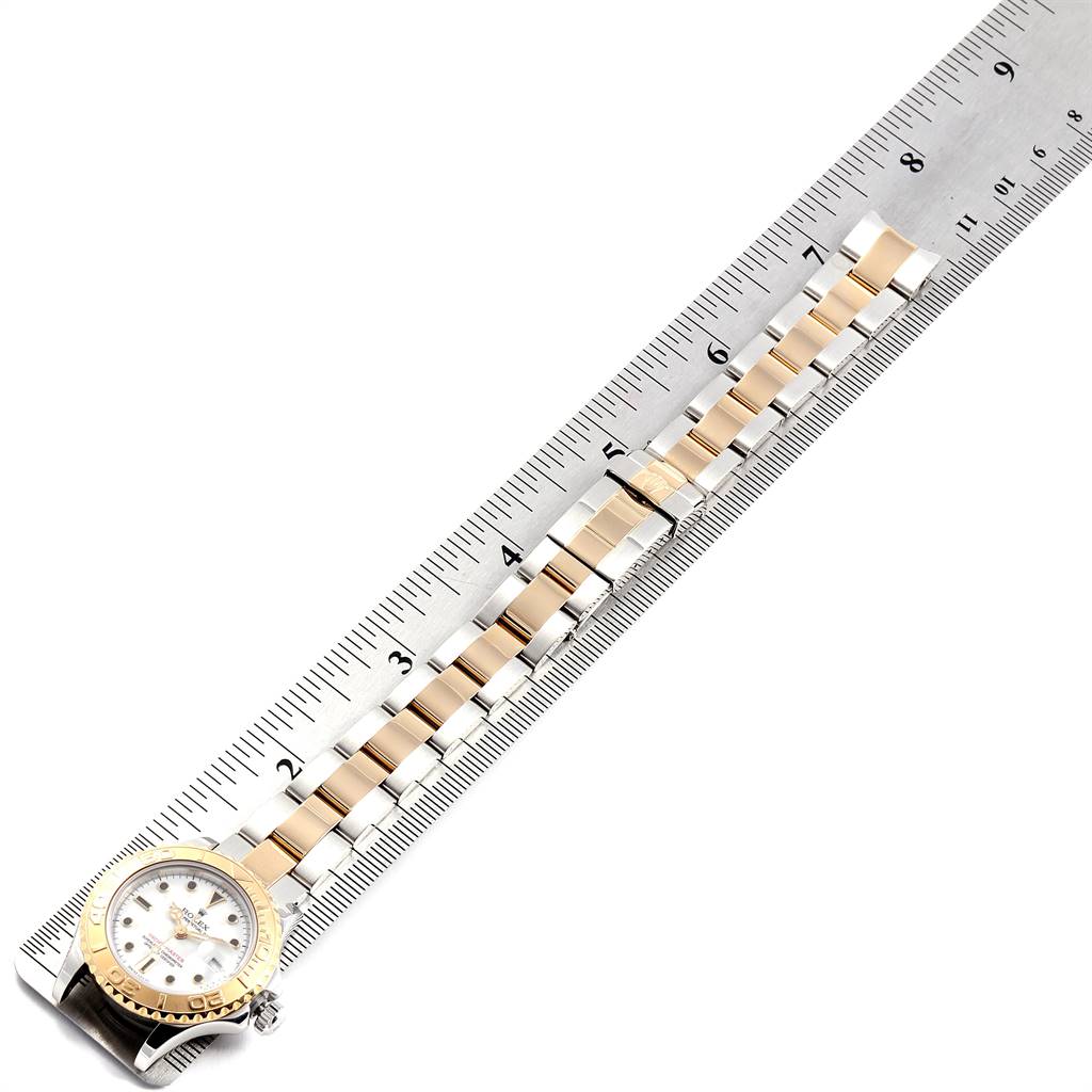 The image shows a top-down view of a Rolex Yacht-Master 69623 Women's Steel and Gold (two tone) White Dial 69623 Women's Steel and Gold (two tone) White Dial watch with its bracelet aligned next to a ruler.