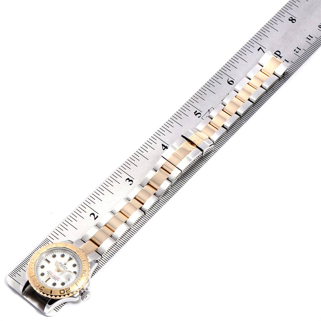 The Rolex Yacht-Master 69623 Women
s Steel and Gold (two tone) White Dial 69623 Women
s Steel and Gold (two tone) White Dial watch is shown from a top view, displaying the dial and bracelet alongside a ruler.