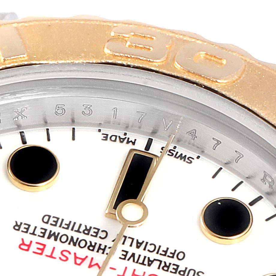 The image shows a close-up of the Rolex Yacht-Master 69623 Women
s Steel and Gold (two tone) White Dial 69623 Women
s Steel and Gold (two tone) White Dial
s bezel, chapter ring, dial, and hands at an angled view.